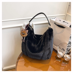 Gros plan d'un sac cabas en peluche noire avec breloque léopard sur table en verre