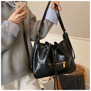 Detail of black quilted bucket bag featuring glossy PU leather and gold zipper