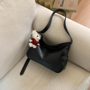 Detail of black crossbody bag with white contrast stitching and a cute bear pendant