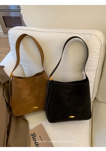 Detail of retro bucket bags in caramel and black on a sofa with metallic accents