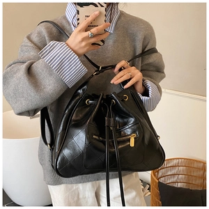 Detail of black quilted leather bucket bag with gold hardware and drawstring closure
