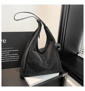 Close-up of a minimalist black hobo tote bag with soft suede texture and metallic buckle
