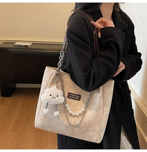 Detail of beige floral jacquard tote with pearl chain strap and plush cloud charm