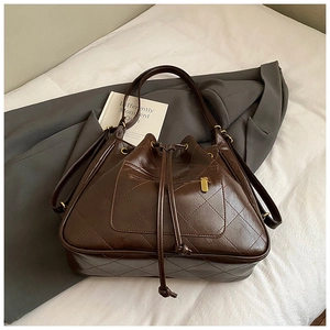Detail of dark brown quilted bucket backpack with golden zipper pocket and drawstring closure