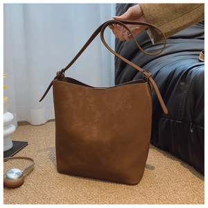 Detail of a vintage large brown bucket bag in matte leather shown in a lifestyle setting