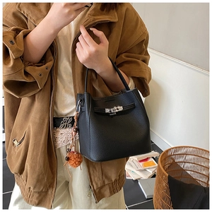 Detail of black lychee grain leather bucket bag with silver buckle and plush charm