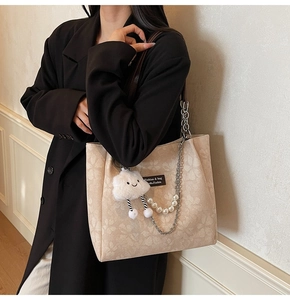 Detail of beige jacquard tote bag with cloud pendant and pearl chain shoulder strap