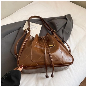Detailed view of brown quilted faux leather bucket bag with drawstring and gold hardware