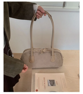 Detail of beige suede baguette bag showing silver double zipper and reinforced stitching