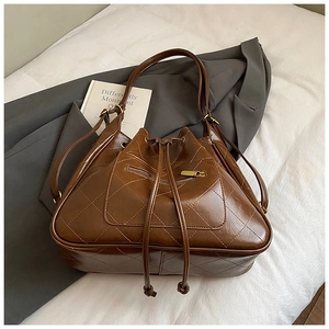 Close-up of brown leather bucket backpack featuring large diamond quilted stitching patterns