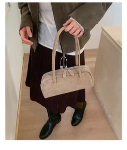 Top view of beige suede Boston bag on wood floor, showing long handles and zipper detail