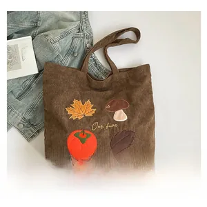Détails de broderie de champignons et feuilles d'automne sur un sac cabas en velours