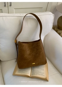Close-up of retro brown bucket bag with gold buckle on book with minimalist vibe