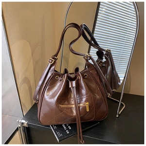 Detail of dark brown quilted leather bucket bag with gold zipper and drawstring closure