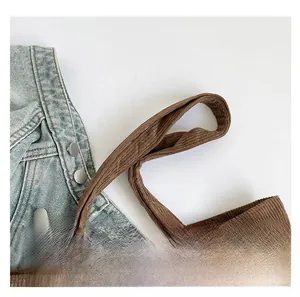 Vue détaillée des poignées d'un sac cabas en velours côtelé marron à rayures