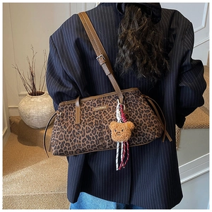 Détail du sac à bandoulière léopard avec bandoulière en cuir brun et pendentif ours