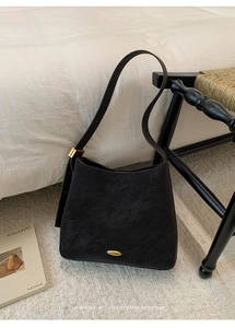 Detailed close-up of a vintage black matte leather shoulder bag with gold metal hardware details