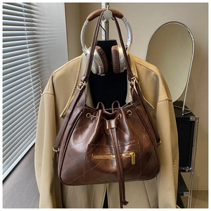 Detail of retro dark brown quilted bucket bag with drawstring closure and gold hardware