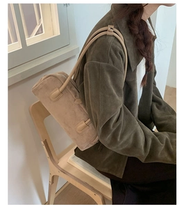 Close-up of retro suede Boston bag in light khaki worn by a model in a natural setting