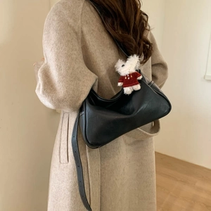 Detail of black leather crescent bag with white contrast stitching and plush bunny charm