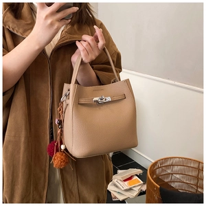 Detail of light brown bucket bag featuring pebble texture and silver twist-lock closure