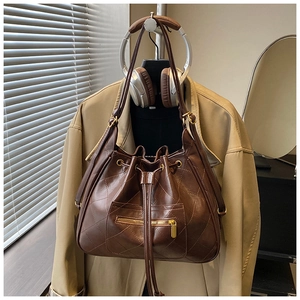 Detail of vintage brown quilted bucket backpack with drawstring and metal zipper pocket
