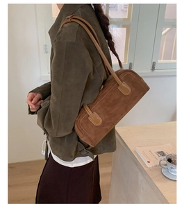 Brown suede-texture Boston bag shown being worn on the shoulder in a minimalist setting