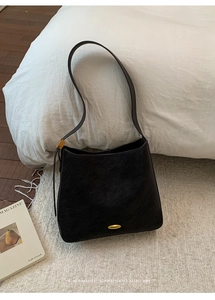 Detail of vintage black matte shoulder bag with elegant gold metal buckle and hardware