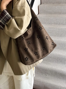 Vintage brown suede tote bag with laser-cut floral patterns shown in a model shot