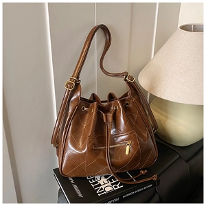 Close-up of quilted dark brown bucket bag with drawstring closure and golden hardware