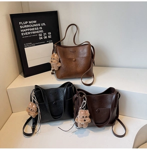 Three leather tote bags in brown, black, and coffee with bear charm and NEW YORK logo