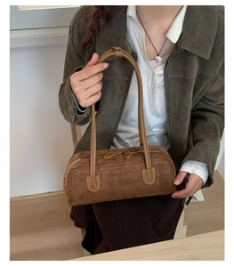 Detail of dark brown suede boston bag texture with sleek leather trim and stitching