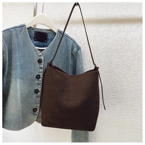 Detail view of dark coffee suede bucket bag with minimalist stitching and slim strap