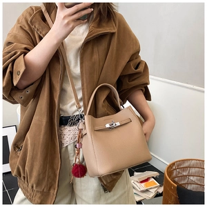 Dettaglio della borsa beige in pelle a grana di litchi con chiusura dorata e ciondolo