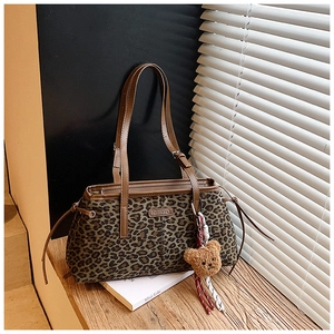 Gros plan sur le sac fourre-tout léopard avec bordure en cuir et breloque ours en peluche