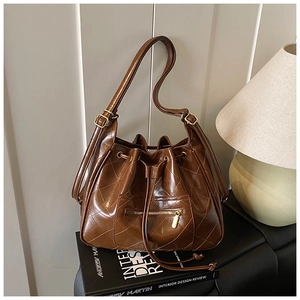 Detail of dark brown quilted leather bucket bag with drawstring and zip pocket