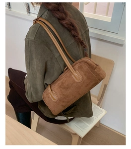 Detail of deep brown suede boston bag with contrast stitching and dual shoulder straps