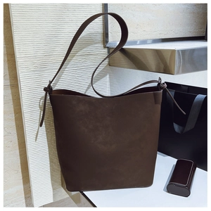 Detail of coffee brown matte leather bucket bag with knotted shoulder strap and large interior