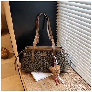 Détail d'un sac cabas à imprimé léopard avec anses brunes et breloque ours peluche