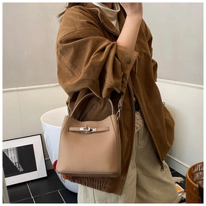 Detail of silver twist-lock closure on light brown lychee grain leather bucket bag