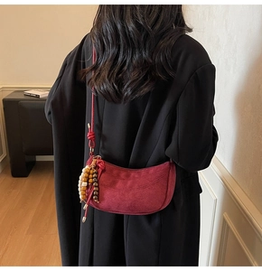 Close-up of red suede half-moon bag featuring beaded tassel and knotted shoulder strap