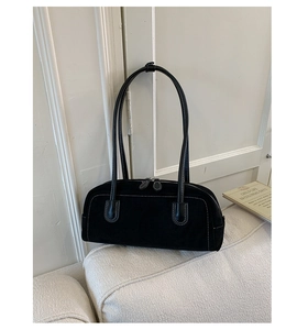 Close-up of black suede underarm bag featuring white contrast stitching and dual zippers