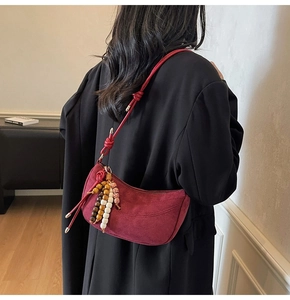 Model wearing a red suede crescent bag with ethnic beads and a slim shoulder strap