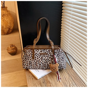 Détail d'un sac cabas à imprimé léopard avec anses en cuir brun et breloque ours