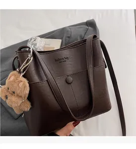Detail of dark brown leather bucket bag with fashion embossing and plush bear charm