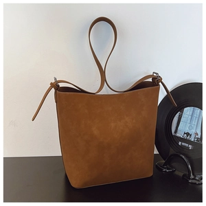 Detail of vintage brown suede bucket bag with metallic buckle on a minimalist desk