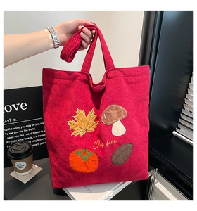 Gros plan du sac cabas en velours côtelé rouge avec broderie de feuilles d'automne