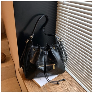 Detail of black quilted bucket bag with golden zipper on a wooden window sill