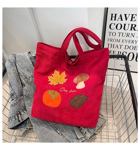 Détail d'un sac cabas en velours côtelé rouge avec broderies d'automne et poignées
