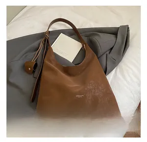 Detail of matte brown leather hobo bag with mini charm and branded MUQIER & BAGS logo